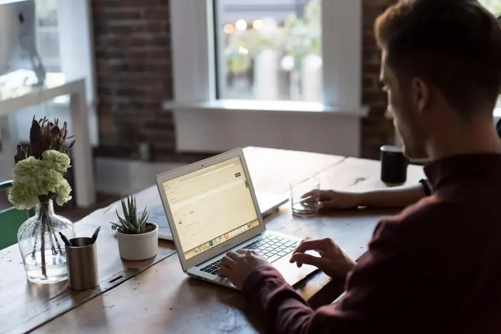 A man using his laptop to work with the best newsletter software for his business.